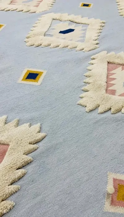 Tapis personnalisé présentant des motifs géométriques dans des tons bleu pastel, rehaussés de motifs traditionnels jaunes et roses.