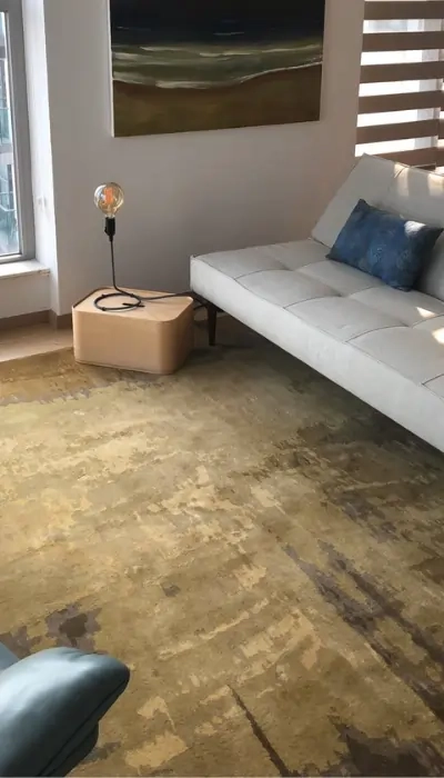 Tapis sur mesure dans des tons dorés terreux, ajoutant chaleur et élégance à un salon moderne avec un mobilier minimaliste.