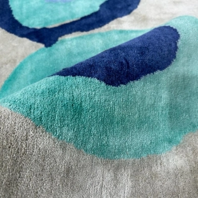 A close-up of a custom handmade rug inspired by children’s artwork, showcasing abstract turquoise and navy blue designs with soft textures on a neutral background.