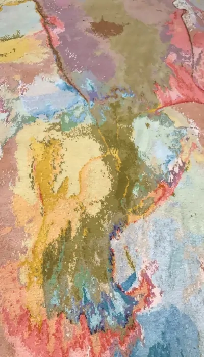 Tapis fait main dans des tons pastel doux de rose, vert et beige, conçu pour évoquer la beauté des paysages naturels.