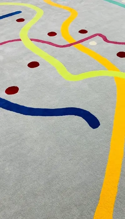 Tapis tufté à la main, gris avec des lignes jaunes, bleues, roses, turquoise et roses. Motif inspiré du métro parisien.