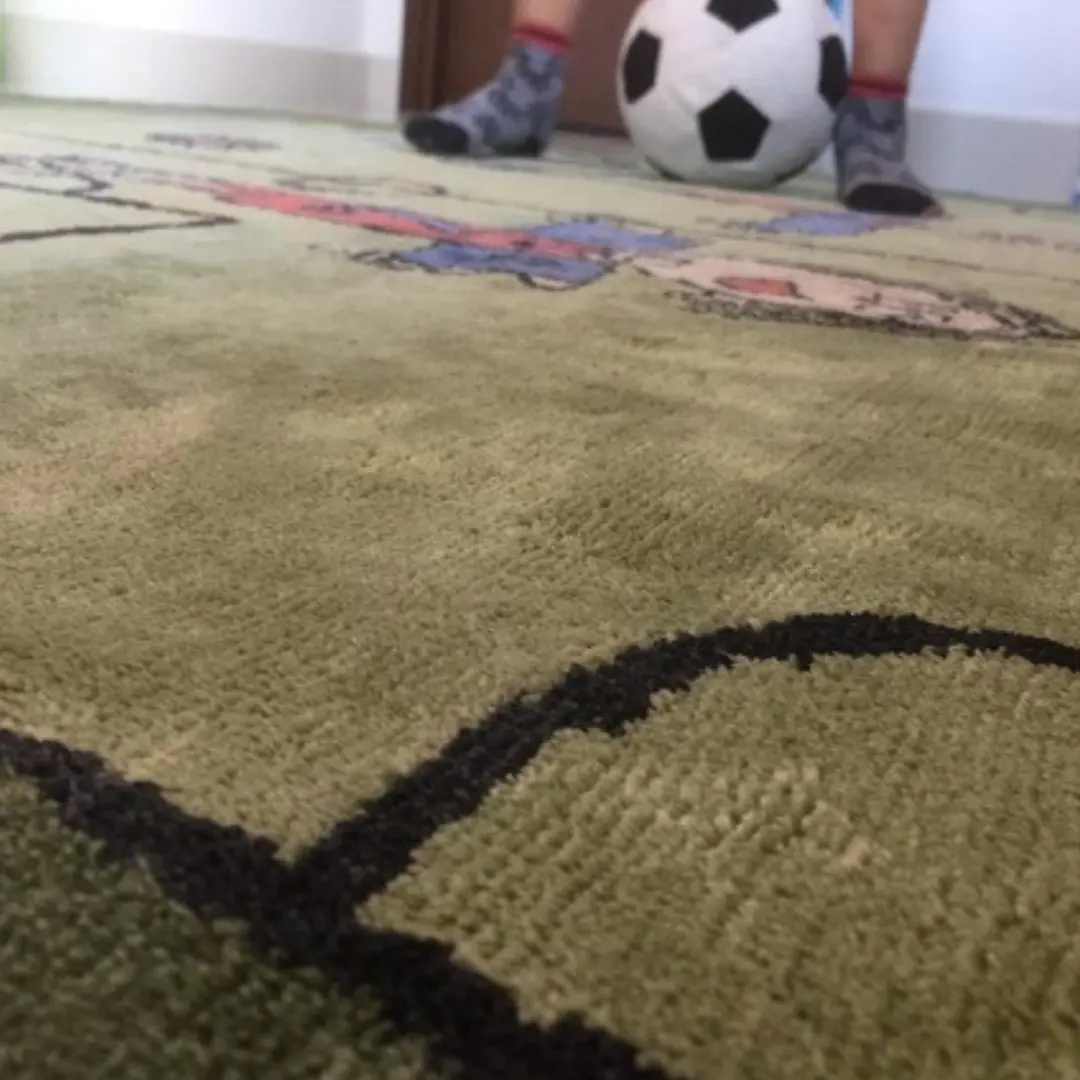 Vista lateral de la alfombra hecha a mano a medida inspirada en el arte infantil y el dibujo de un partido de fútbol