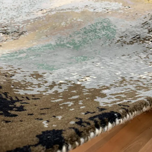 Gros plan sur un tapis noué à la main sur mesure d'après la peinture abstraite de l'artiste Ashley January, dans des tons bruns, gris, blancs et noirs.