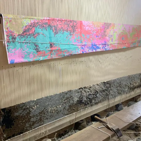 Processus de tissage du tapis noué à la main sur mesure d'après la peinture abstraite de l'artiste Ashley January, dans des tons bruns, gris, blancs et noirs.
