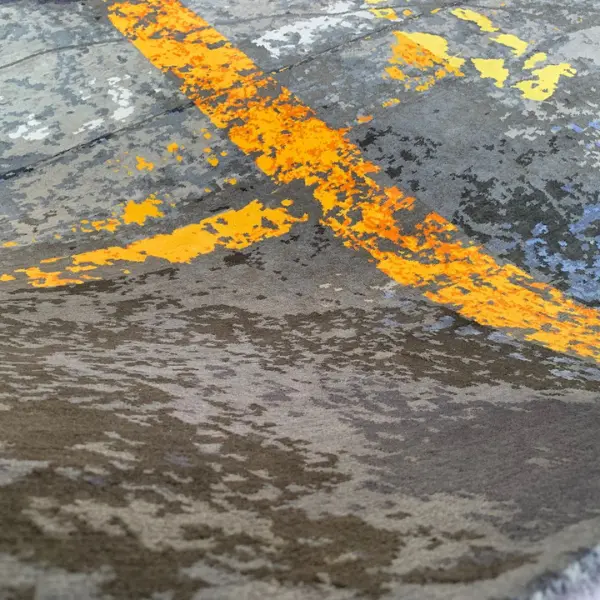 Gros plan sur un tapis fait main sur mesure en gris et jaune d'après la photo d'un sol d'usine du client.