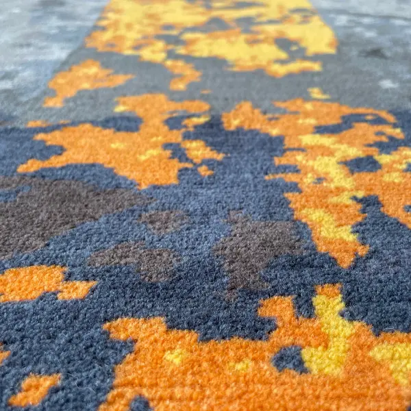 Gros plan sur un tapis fait main sur mesure en gris et jaune d'après la photo d'un sol d'usine du client.