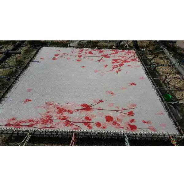 Le savoir-faire artisanal à l'origine d'un tapis sur mesure pour compléter un salon d'inspiration japonaise, avec des fleurs de cerisier en gris et en rose