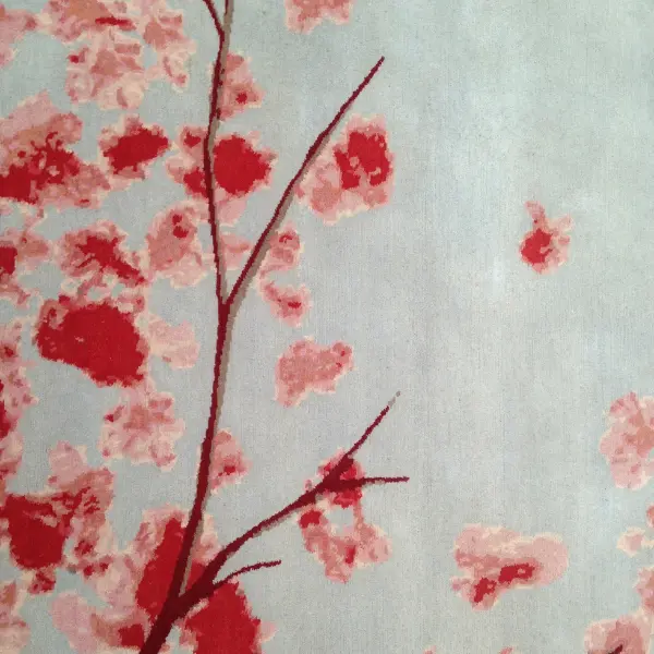 Gros plan sur un tapis fait sur mesure pour compléter un salon d'inspiration japonaise, avec des fleurs de cerisier en gris et en rose.
