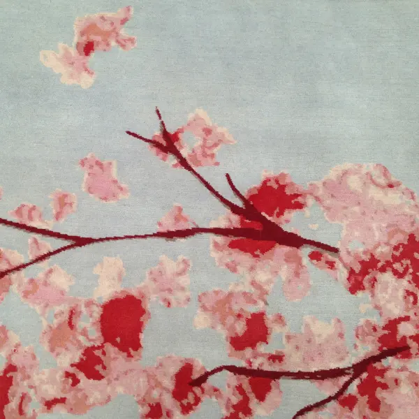 Gros plan sur un tapis fait sur mesure pour compléter un salon d'inspiration japonaise, avec des fleurs de cerisier en gris et en rose.