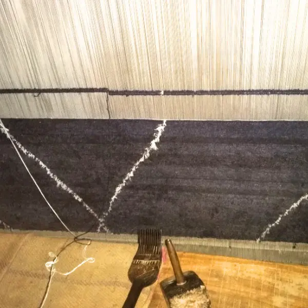 Artisanat derrière un tapis noué à la main en ortie noire pour un projet de décoration d'intérieur. Design simple, effet vintage fait à la main
