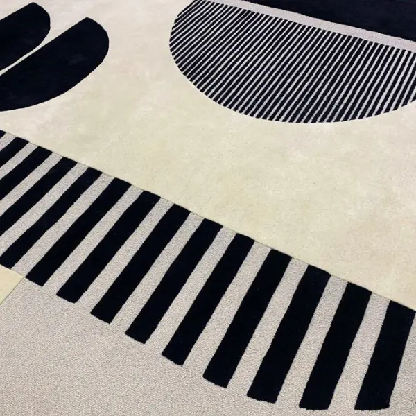 Gros plan sur un tapis fait main pour un projet de décoration d'intérieur, noir et crème, avec des rayures et des demi-cercles, différentes textures et hauteurs de poils.