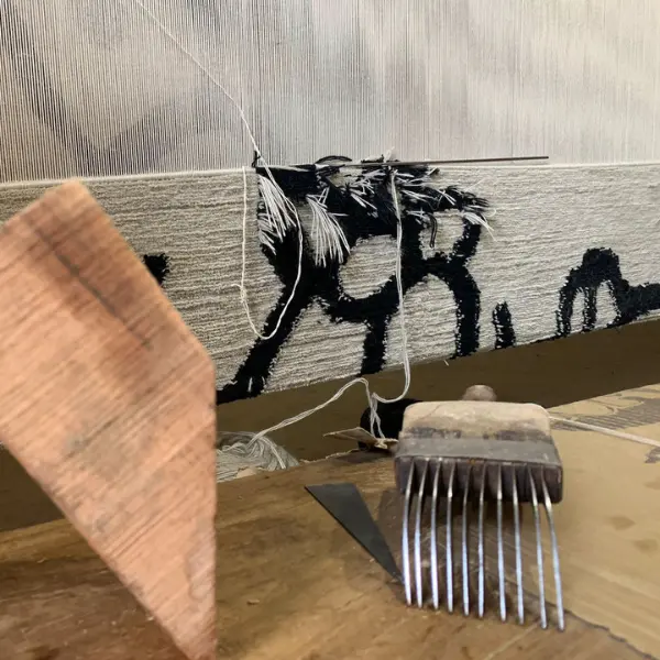 Un savoir-faire authentique pour créer ce tapis moderne, minimaliste et unique, noué à la main sur mesure, de couleur crème avec des lignes noires.