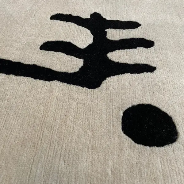 Gros plan sur un tapis sur mesure moderne, minimaliste et unique, noué à la main, de couleur crème, avec un dessin au trait noir.