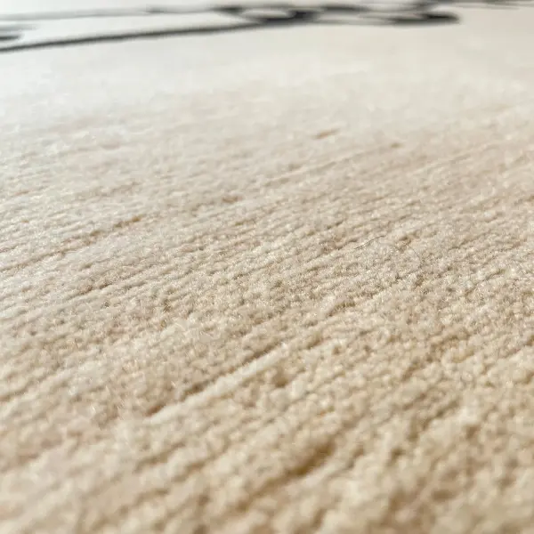 Gros plan sur un tapis sur mesure moderne, minimaliste et unique, noué à la main, de couleur crème, avec un dessin au trait noir.
