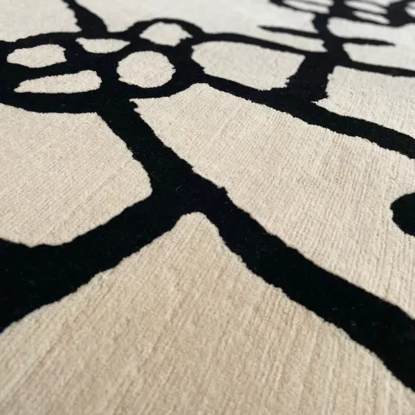 Gros plan sur un tapis sur mesure moderne, minimaliste et unique, noué à la main, de couleur crème, avec un dessin au trait noir.