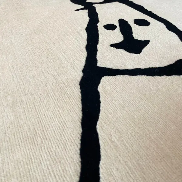 Gros plan sur un tapis sur mesure moderne, minimaliste et unique, noué à la main, de couleur crème, avec un dessin au trait noir.