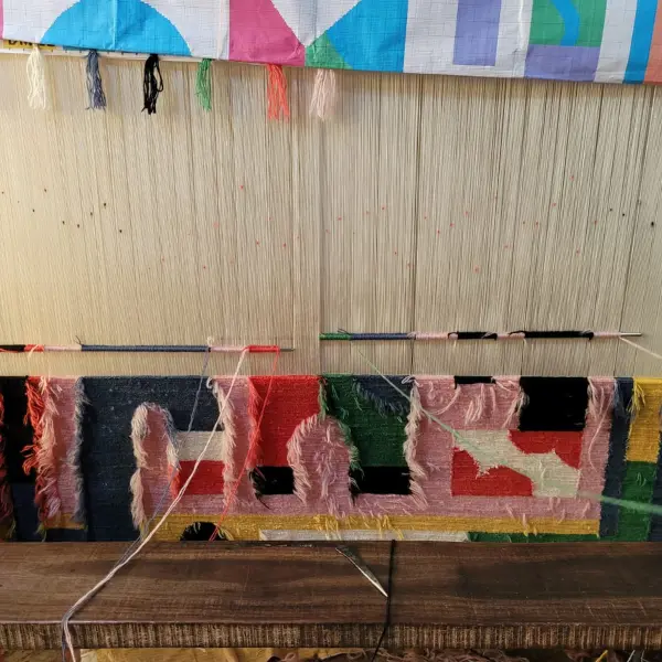 Tissage Tapis rose et coloré noué à la main avec des lettres graphiques dessinées par l'artiste italienne Camilla Falsini