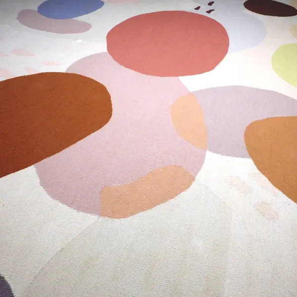 Gros plan sur un kilim rond réalisé à partir d'une aquarelle de l'artiste textile Ella Hartweger, dans de magnifiques tons pastel et avec des formes rondes qui se chevauchent.