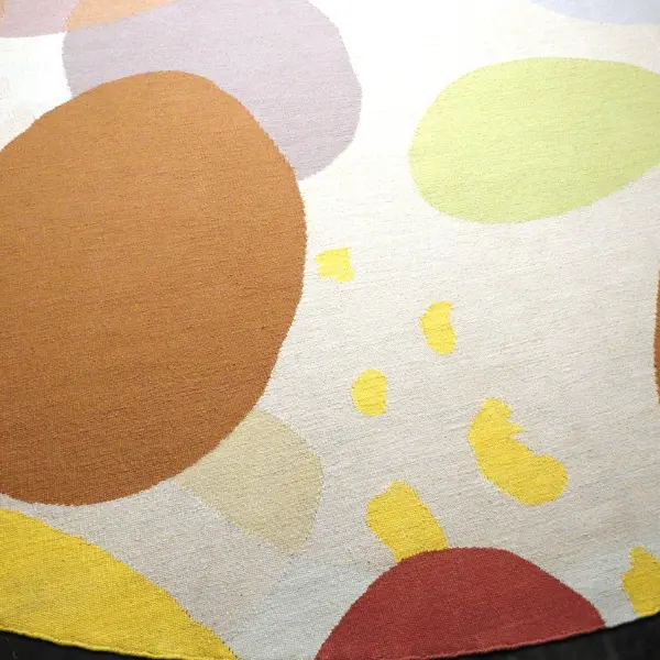 Gros plan sur un kilim rond réalisé à partir d'une aquarelle de l'artiste textile Ella Hartweger, dans de magnifiques tons pastel et avec des formes rondes qui se chevauchent.