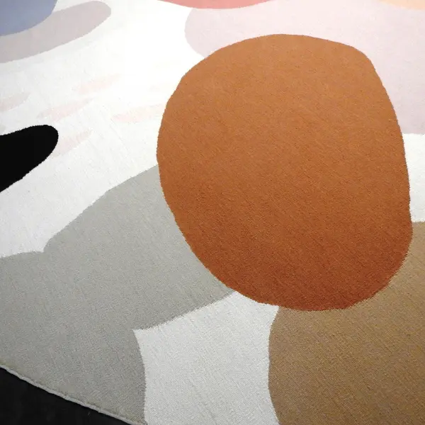 Gros plan sur un kilim rond réalisé à partir d'une aquarelle de l'artiste textile Ella Hartweger, dans de magnifiques tons pastel et avec des formes rondes qui se chevauchent.