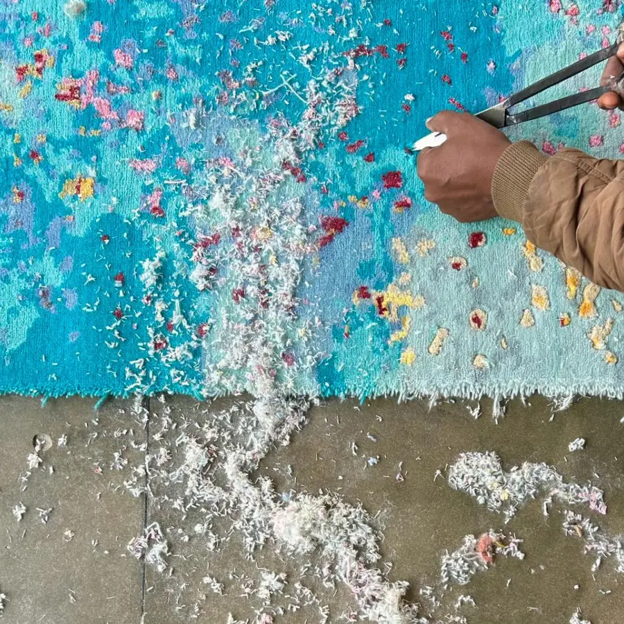 Artisan carving the details of a turquoise rug designed by Sabine Oecking